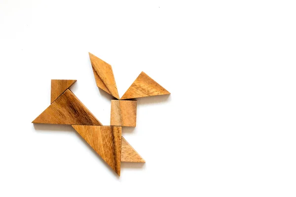 Wooden tangram as running rabbit shape on white background