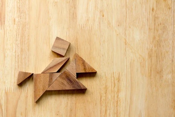 Tangram puzzle in man ride the horse boat shape on wood background — Stok Foto