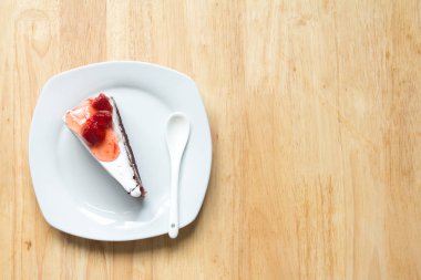 Ahşap arka plan üzerinde beyaz plaka ile Çilekli pasta