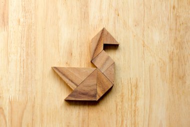 Ahşap arka plan üzerinde kuğu şeklinde bulmaca Tangram