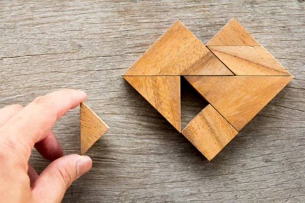 Man held piece of tangram puzzle to meet the heart shape on wooden table (Conceito de amor ) — Fotografia de Stock