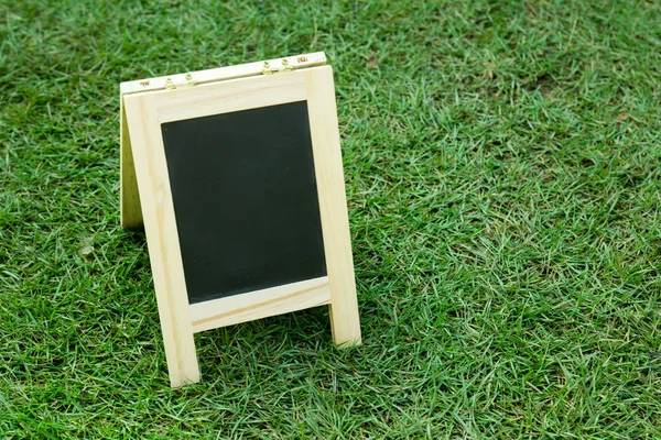 Placa preta em branco com cavalete no fundo de grama verde — Fotografia de Stock