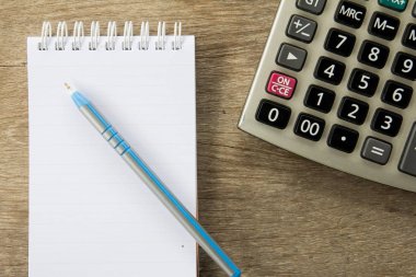 Ahşap masa arka plan üzerinde kalem ve hesap makinesi ile Not kitabın Üstten Görünüm