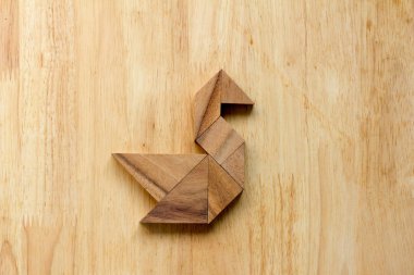Ahşap arka plan üzerinde kuğu şeklinde bulmaca Tangram
