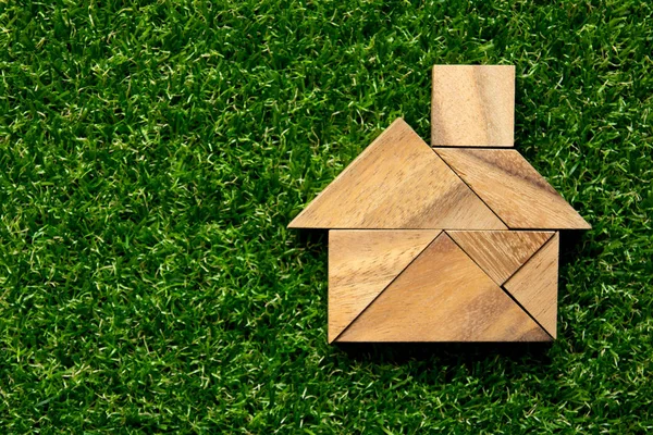 Tangram quebra-cabeça em forma de casa no fundo de grama verde artificial (Conceito para casa dos sonhos ) — Fotografia de Stock