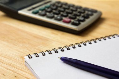 Ahşap masa arka plan üzerinde kalem ve hesap makinesi ile not defteri
