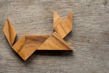Bulmaca Çince tangram şekil ahşap arka plan üzerinde oturan kedi