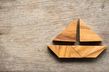 Tangram bulmacanın ahşap arka plan üzerinde yelken tekne şeklinde