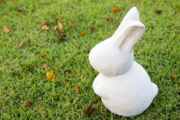 White stone rabbit statue on green grass background — Stock Photo, Image