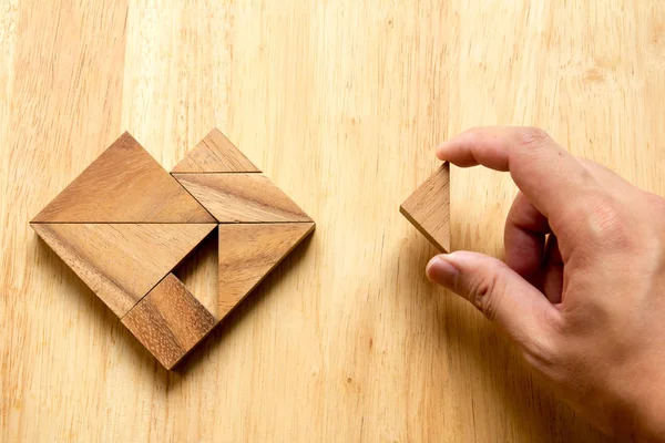 Muž držel kus tangram puzzle plnit tvar srdce na w — Stock fotografie