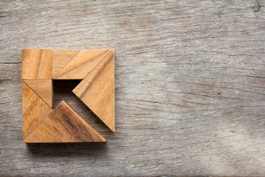 Tangram bulmacanın ahşap arka plan (iş yönetmeni ve karar kavramı üzerinde kare şeklinde ok gibi)