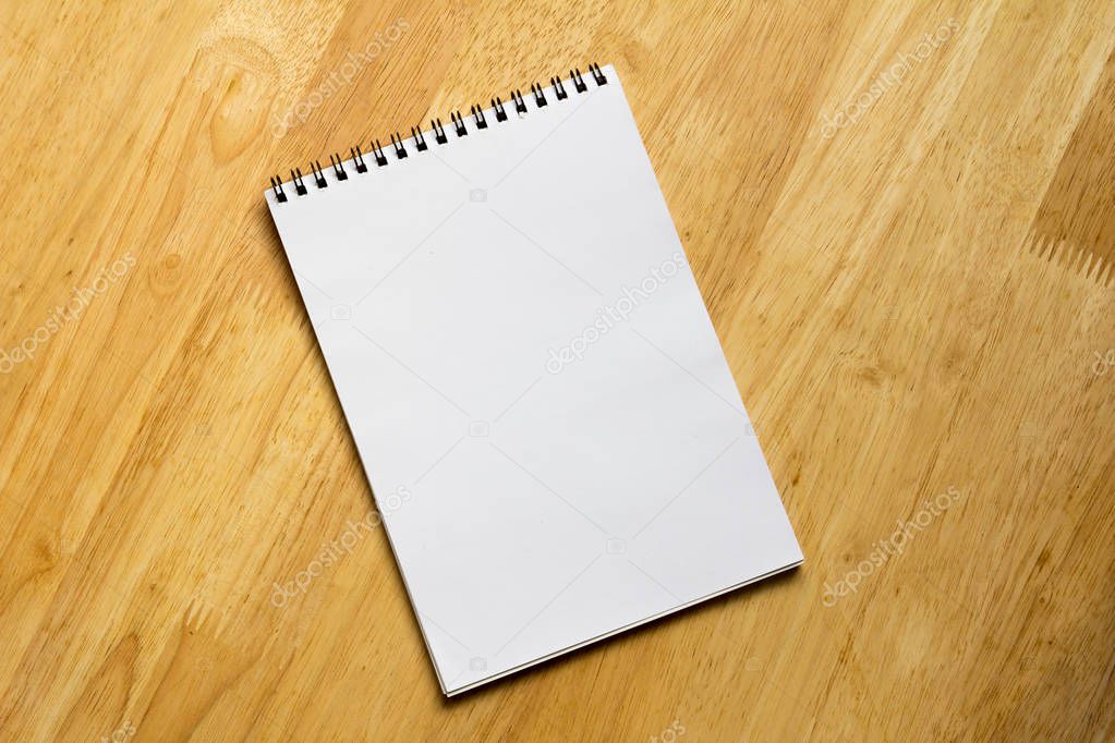 White note book place on wooden table background