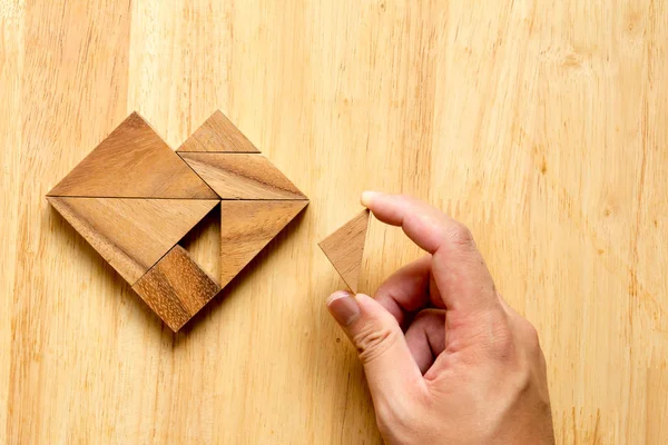 Uomo tenuto pezzo di puzzle tangram per soddisfare la forma del cuore su w — Foto Stock