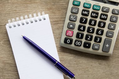 Ahşap masa arka plan üzerinde kalem ve hesap makinesi ile Not kitabın Üstten Görünüm