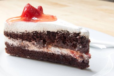 Ahşap arka plan üzerinde beyaz plaka ile Çilekli pasta