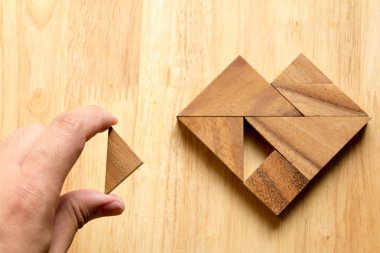 Tangram bulmacanın parçası düzenlenen adam ahşap masa (aşk kavramı üzerinde kalp şekli yerine getirmek için)