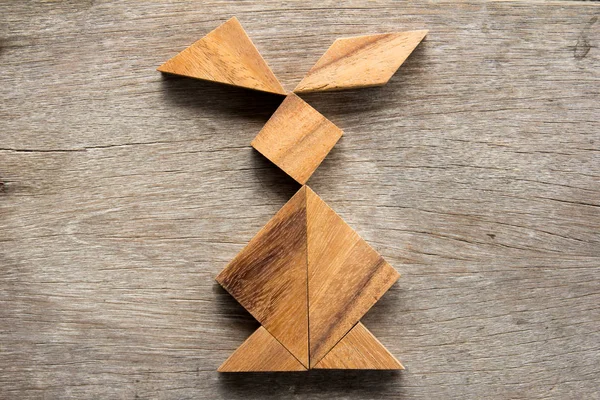 Čínské tangram puzzle ve tvaru králíka na dřevěné pozadí (koncept pro Velikonoce) — Stock fotografie