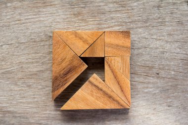 Tangram bulmacanın ahşap arka plan (iş yönetmeni ve karar kavramı üzerinde kare şeklinde ok gibi)