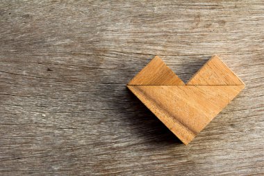 Tangram bulmacanın ahşap arka plan üzerinde kalp şeklinde