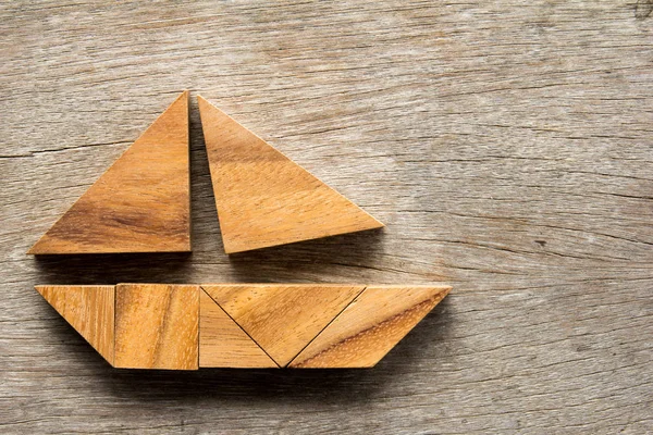 Tangram quebra-cabeça em forma de barco à vela no fundo de madeira — Fotografia de Stock