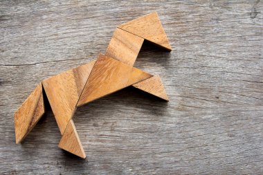 Tangram bulmacanın ahşap arka plan üzerinde at heyecan verici şeklinde