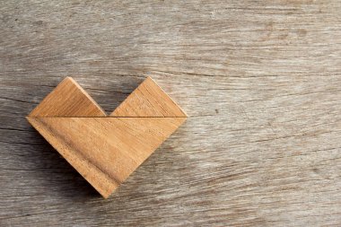 Tangram bulmacanın ahşap arka plan üzerinde kalp şeklinde