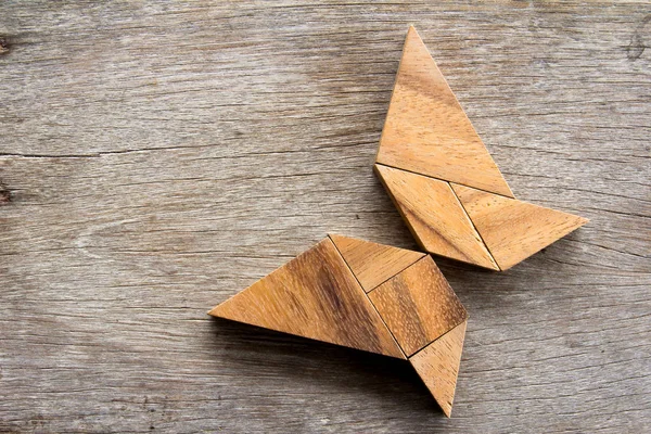 Дерев'яна головоломка танграм на фоні літаючої форми метелика — стокове фото