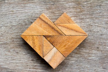Tangram bulmacanın ahşap arka plan üzerinde kalp şeklinde
