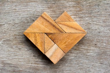 Tangram bulmacanın ahşap arka plan üzerinde kalp şeklinde