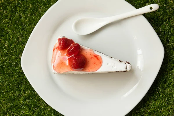 Φράουλα τούρτα με πλάκα και κουτάλι στο πράσινο γρασίδι β — Φωτογραφία Αρχείου