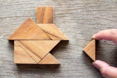 Yapı rüya ev veya mutlu yaşam konsepti için ev şekli yerine getirmek için ahşap tangram bulmacanın bekle