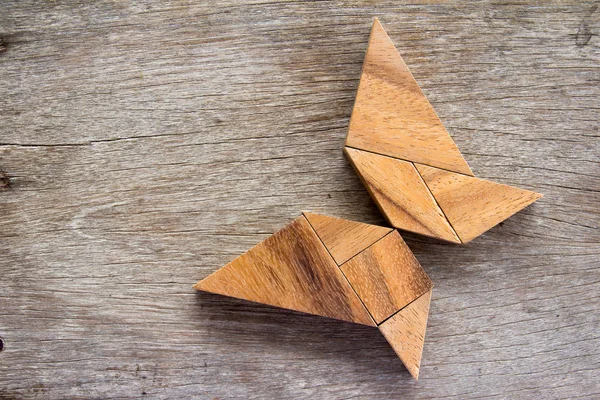 Wooden tangram puzzle in flying butterfly shape background