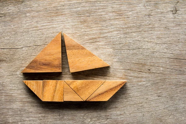 Tangram puzzle ve tvaru člunu plachtu na dřevěné pozadí — Stock fotografie