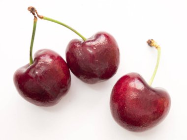 Beyaz zemin üzerinde üç kırmızı kiraz