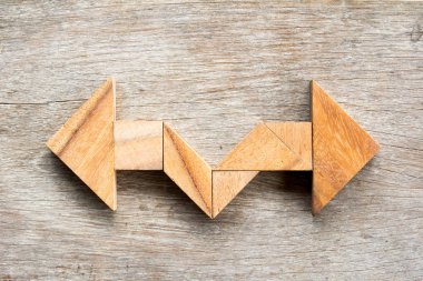 Ahşap arka plan üzerinde iki şekilde ok şekli olarak bulmaca Tangram