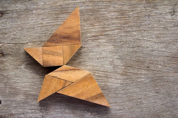 Dřevěný tangram puzzle v létající motýl obrazec pozadí — Stock fotografie