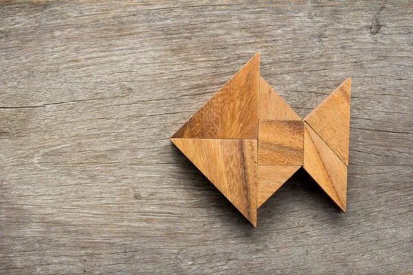 Chinês tangram quebra-cabeça em forma de peixe no fundo de madeira — Fotografia de Stock