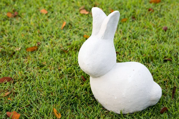 녹색 잔디 배경에 흰색 돌 토끼 동상 — 스톡 사진