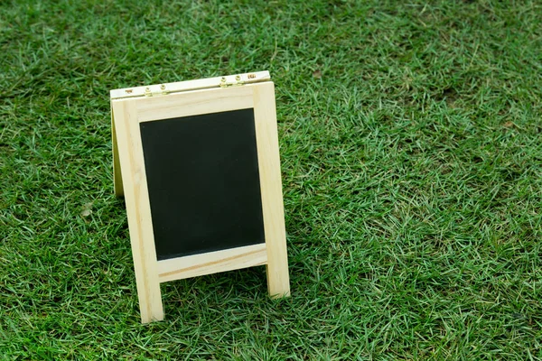 Placa preta com cavalete no fundo de grama verde — Fotografia de Stock