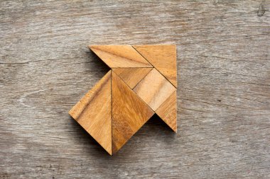 Tangram bulmacanın ahşap arka plan üzerinde ok şeklinde