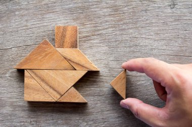 Wooden tangram puzzle wait to fulfill home shape for build dream home or happy life concept clipart
