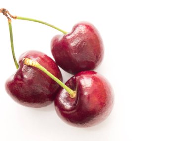 Beyaz zemin üzerinde üç kırmızı kiraz