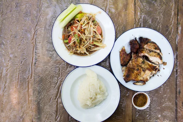 Тайский салат из папайи (Somtum), курица на гриле и липкий рис на деревянном фоне — стоковое фото