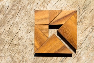Tangram bulmacanın ahşap arka plan (iş yönetmeni ve karar kavramı üzerinde kare şeklinde ok gibi)