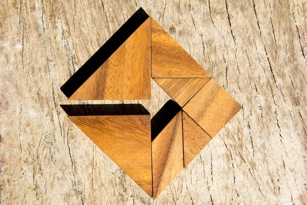 Γρίφος τανγκράμ ως βέλος σε τετράγωνο σχήμα σε ξύλινο υπόβαθρο (έννοια για επαγγελματίες κατεύθυνσης και αποφάσεων) — Φωτογραφία Αρχείου