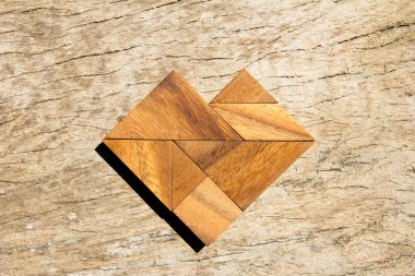 Tangram bulmacanın ahşap arka plan üzerinde kalp şeklinde