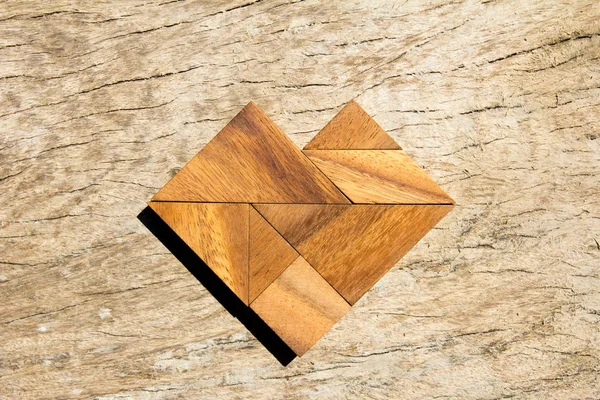Tangram quebra-cabeça em forma de coração no fundo de madeira — Fotografia de Stock