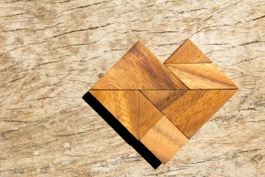 Tangram bulmacanın ahşap arka plan üzerinde kalp şeklinde