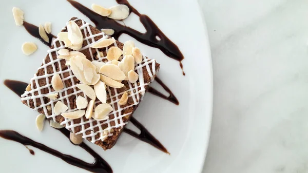 Felülnézet a csokis brownie, szeletelt mandula, fehér lemez — Stock Fotó