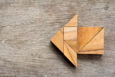 Tangram bulmacanın ahşap arka plan üzerinde ok şeklinde